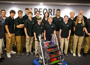 Robotics team posing in district board room